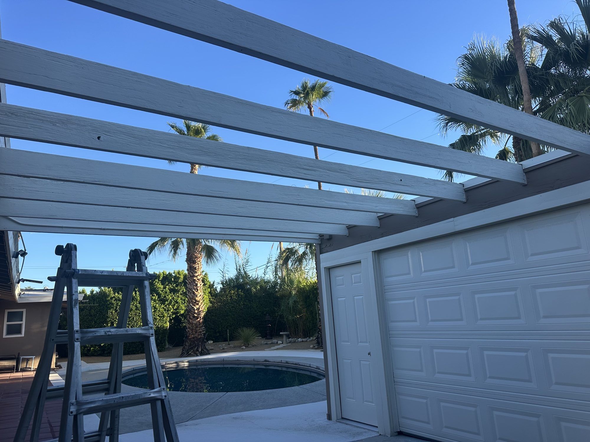Ladder set up under a backyard patio cover during a repair